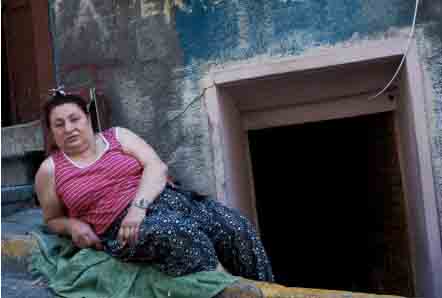 Une femme tzigane posant allongée en face de sa maison.